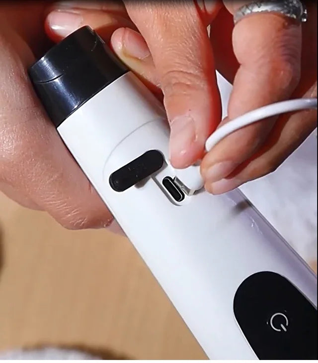 BARESY cordless electric cleaning brush being charged via USB C port with hands inserting cable
