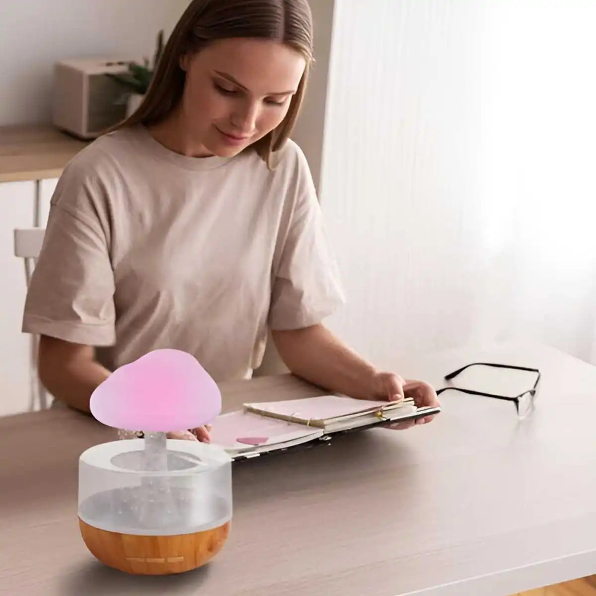 BARESY USB mini humidifier essential oil diffuser with pink mushroom top and wood grain base on desk with woman reading at table
